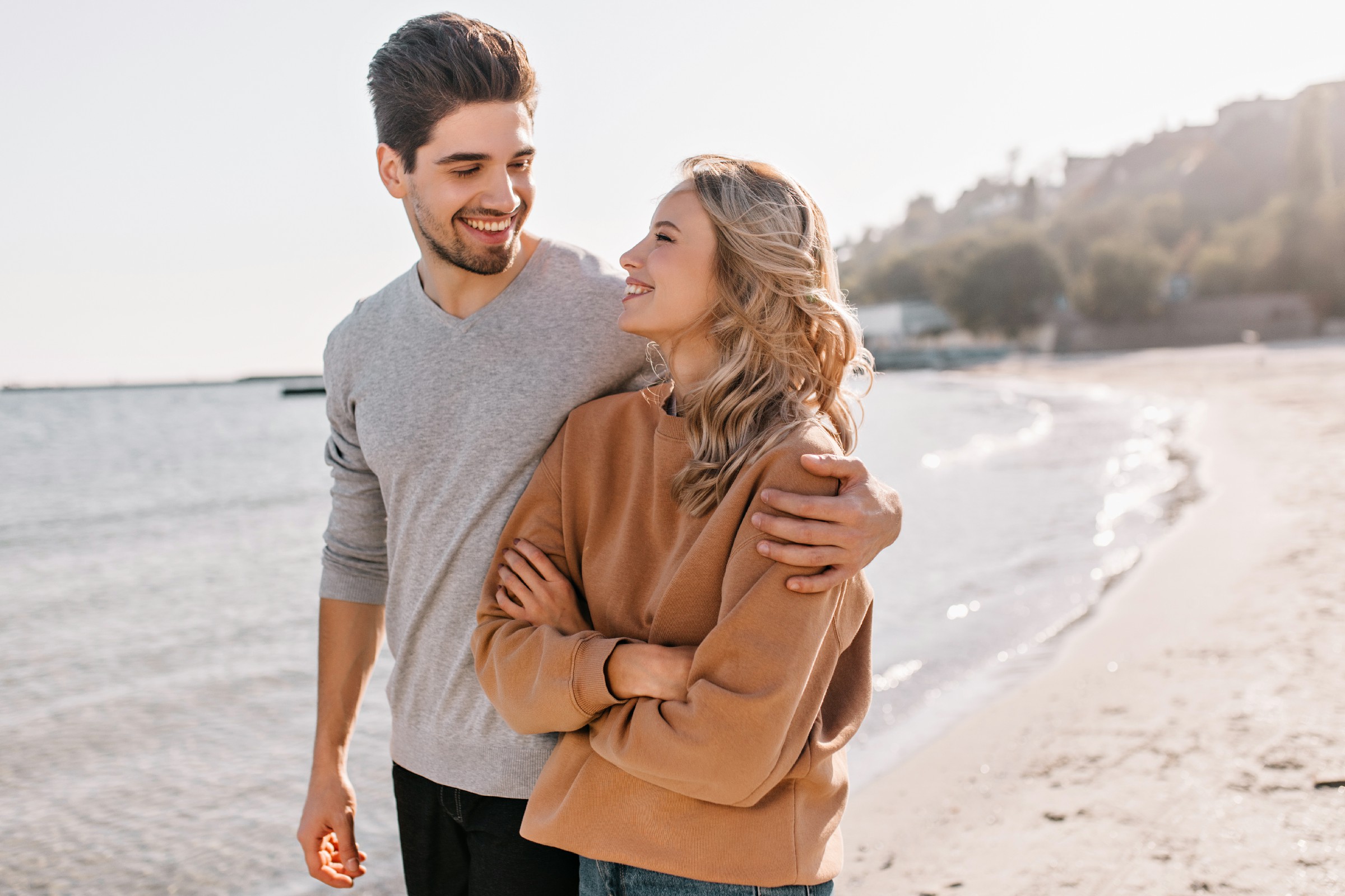 pleasant-young-man-embracing-girlfriend-nature-outdoor-portrait-pleased-blonde-girl-posing-sea-with-husband~1